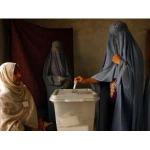 An Afghan Woman Wearing a Burqa Casts Her Ballot at a Polling Station 